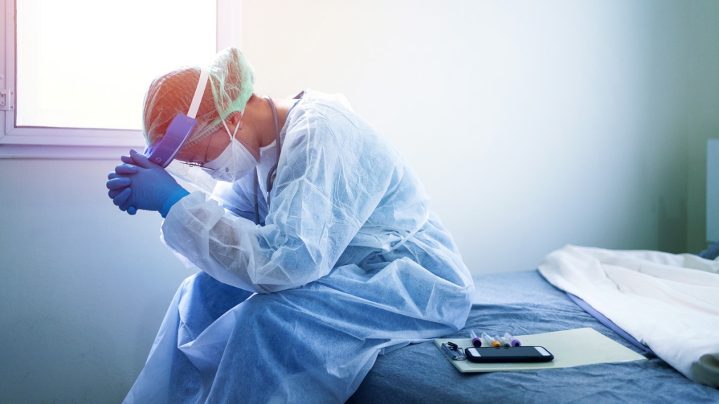 Image of tired doctor in PPE. Mortality risk factors include old age, underlying health conditions, and bacterial and respiratory co-infections: Frontiers in Medicine